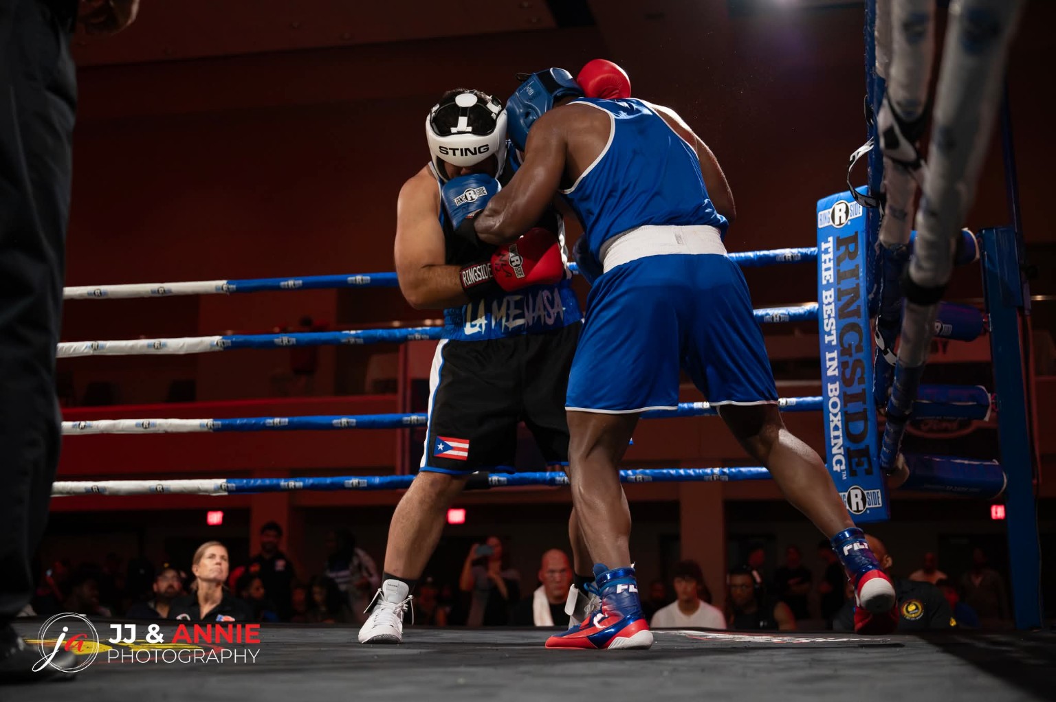 Two amateur boxers exchange punches at close range beside the corner ropes