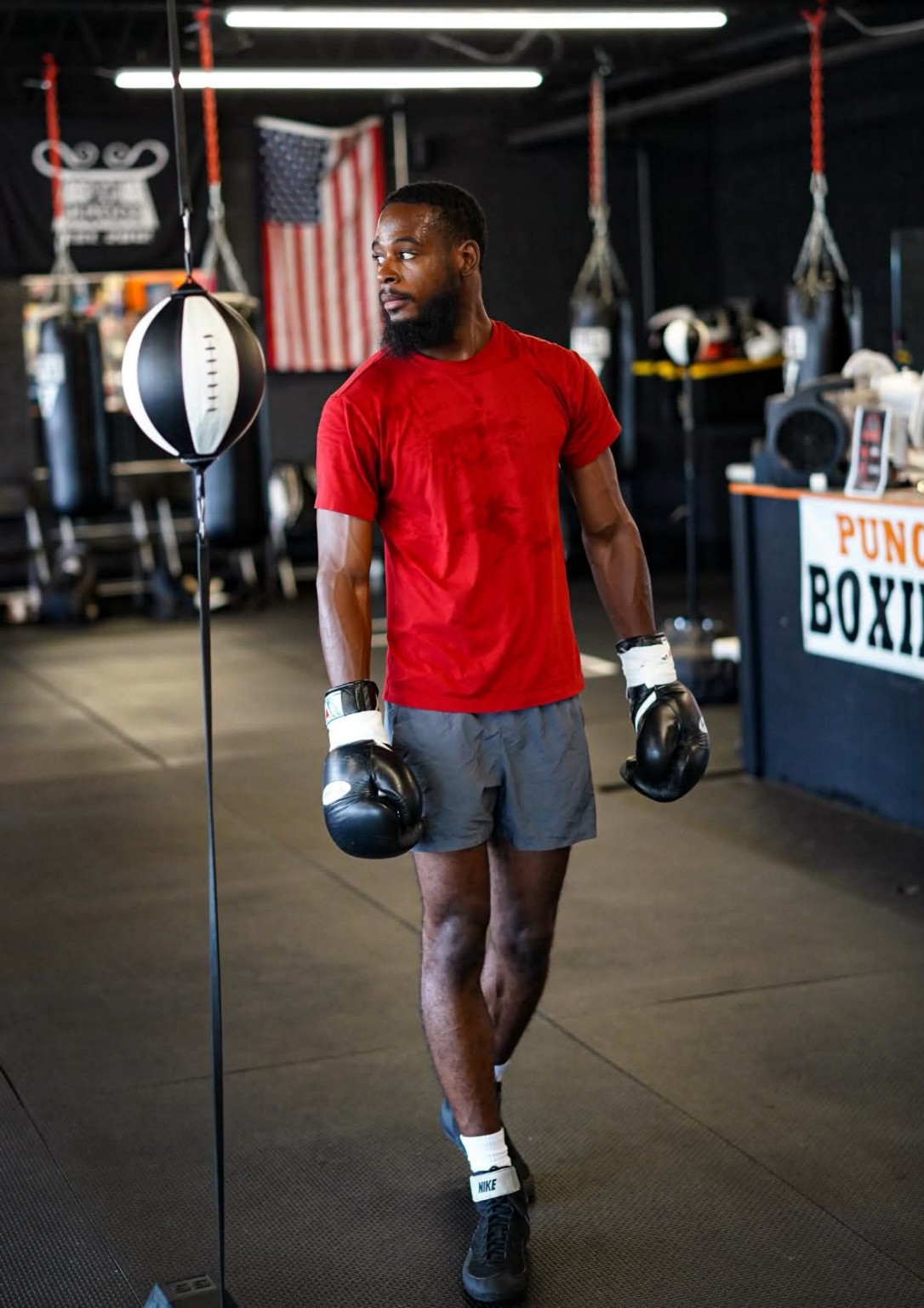 Boxer in gloves training beside a double-end bag during a personal training session.