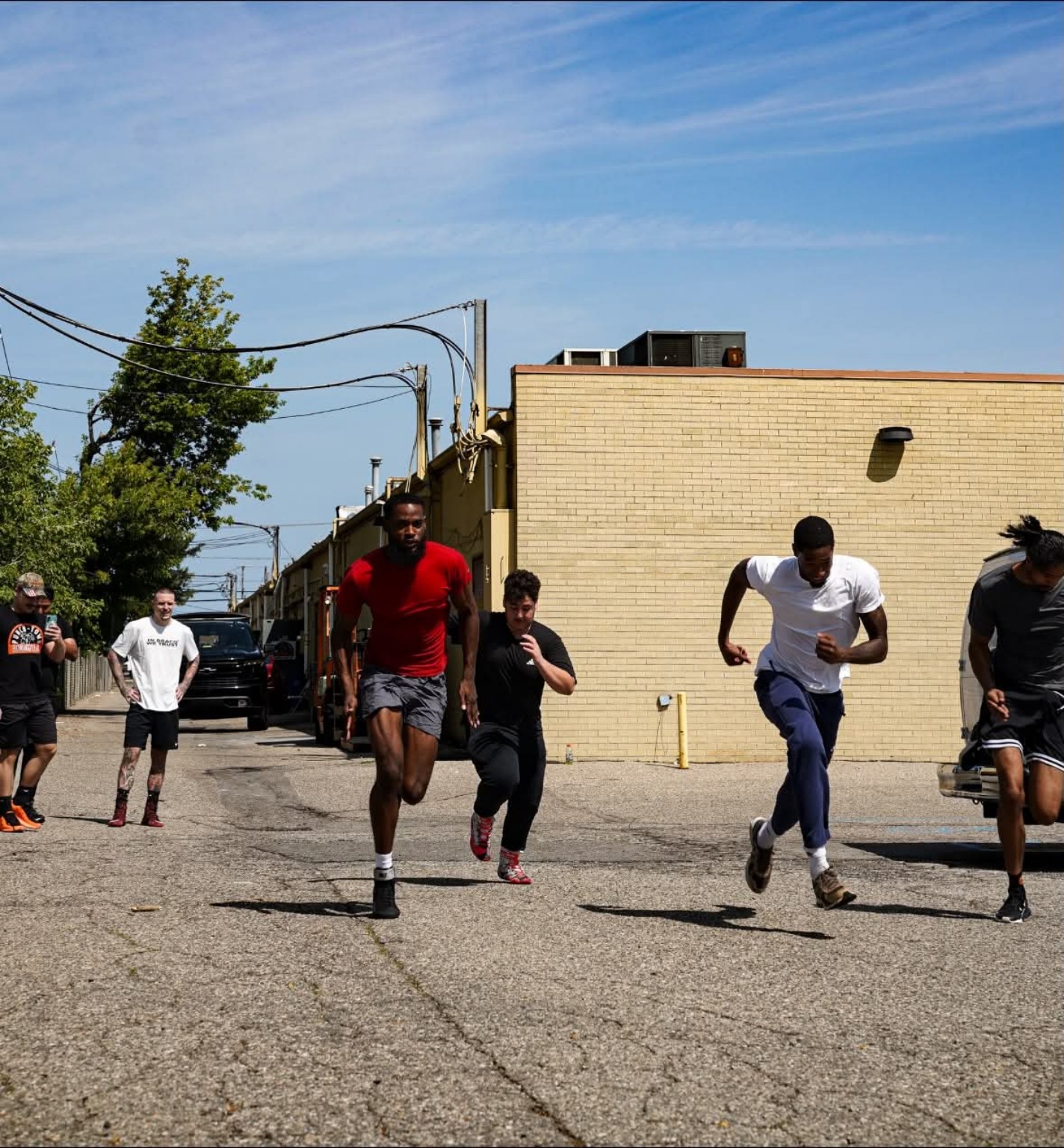 A group of boxers runs sprints together outside the gym during conditioning