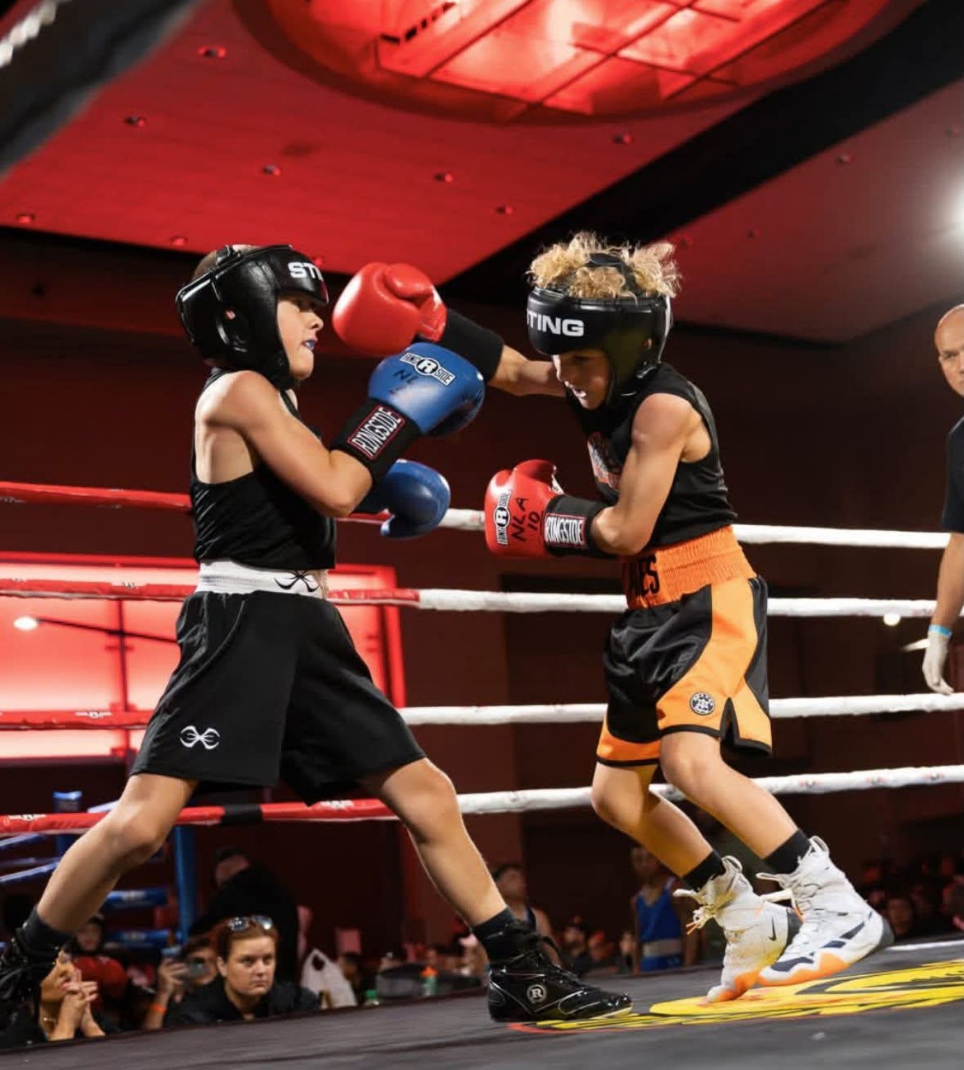 Two young amateur boxers trade punches during a match