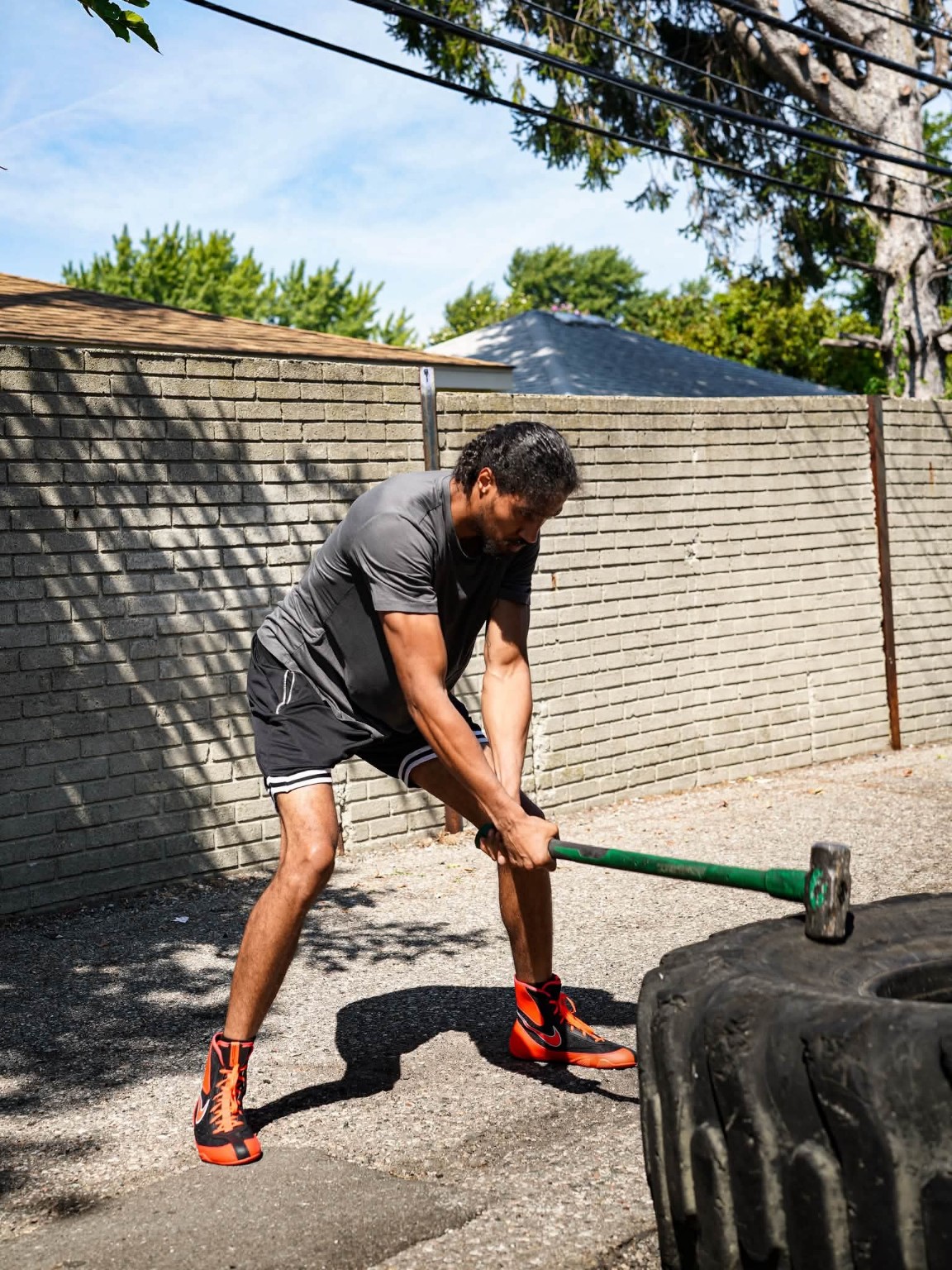 A boxer swings a sledgehammer on a tire during an outdoor conditioning workout