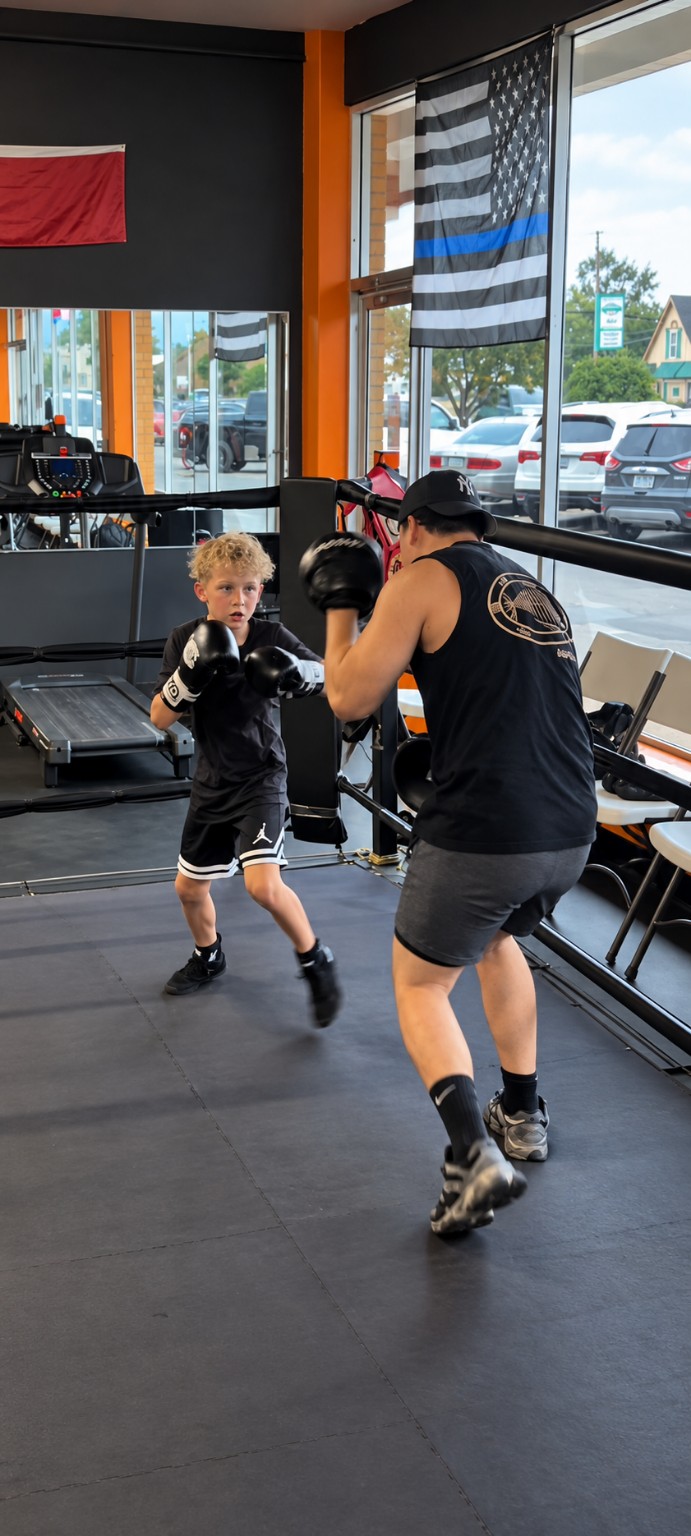 Coach and young boxer working on movement and combinations inside the ring.