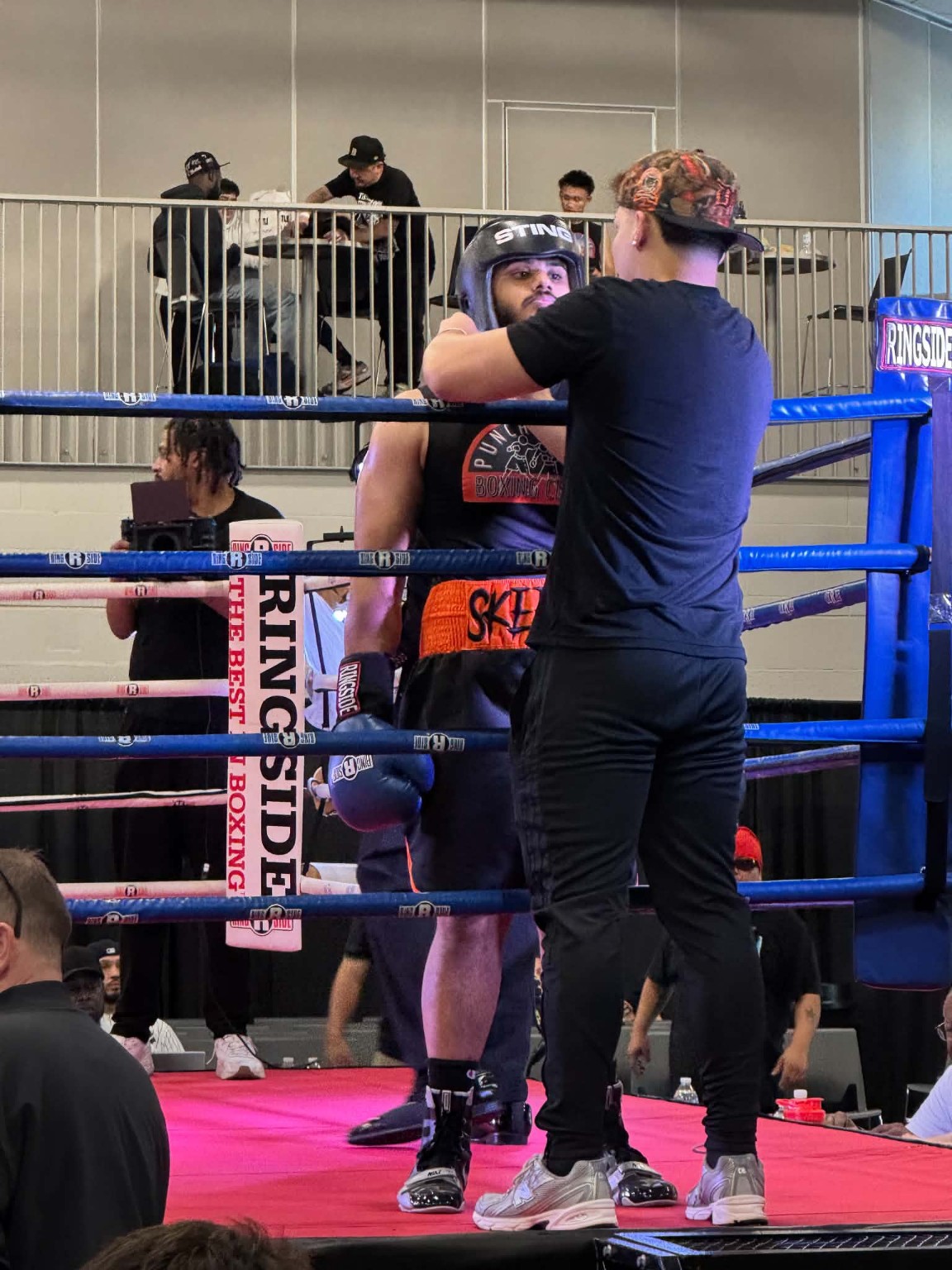 A PunchTown coach giving instructions to an amateur boxer in the corner during a bout