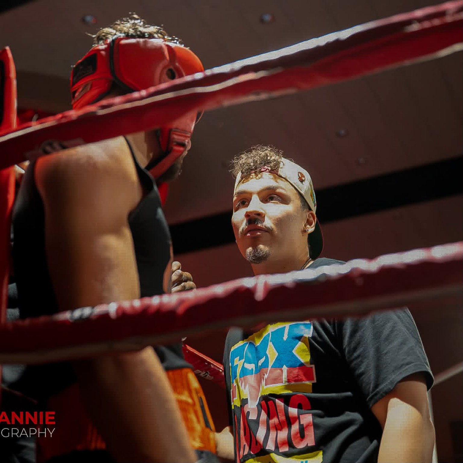 Focused ringside coaching for an amateur boxer wearing red headgear between rounds