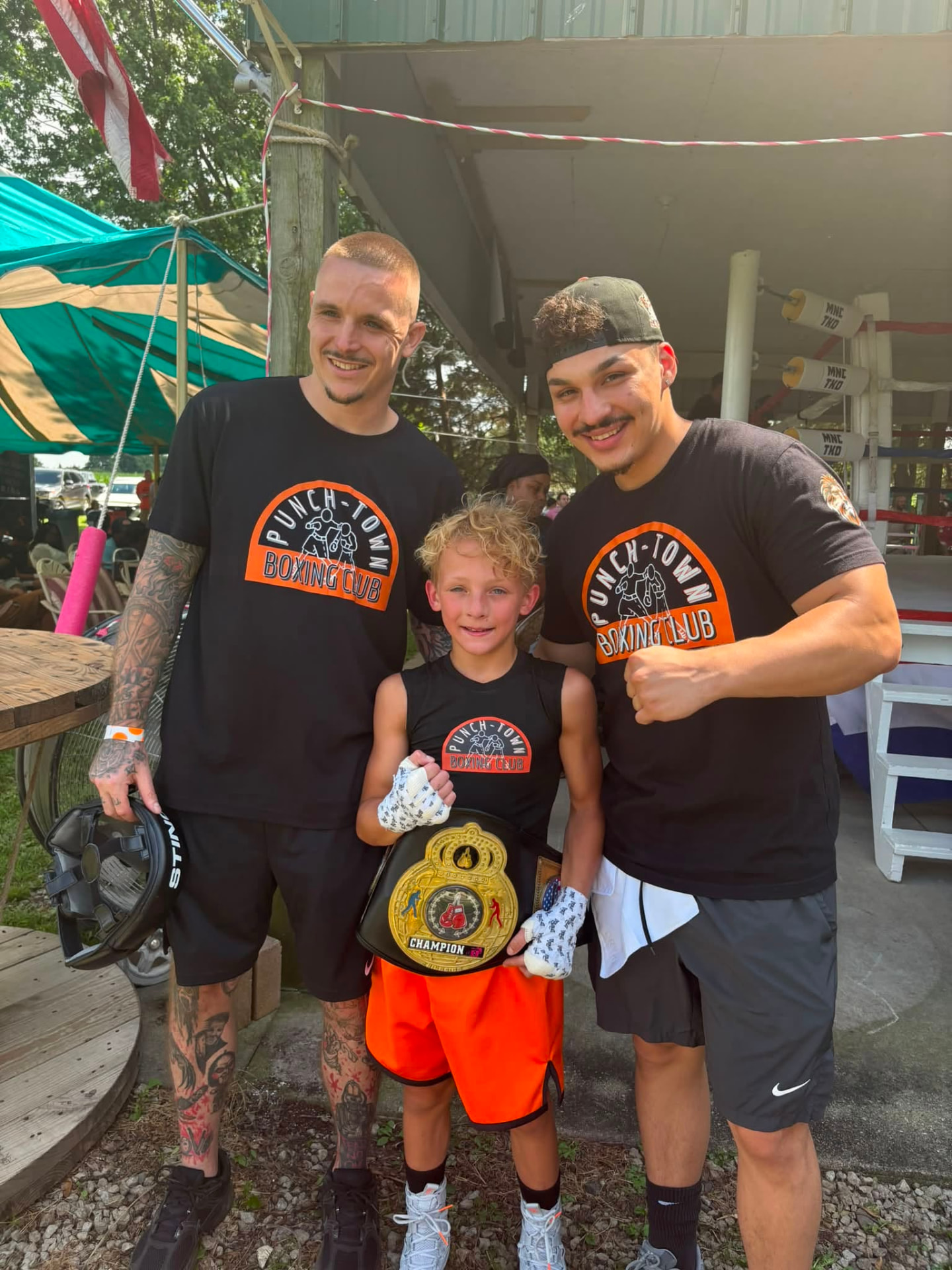 PunchTown coaches with a young champion holding a title belt