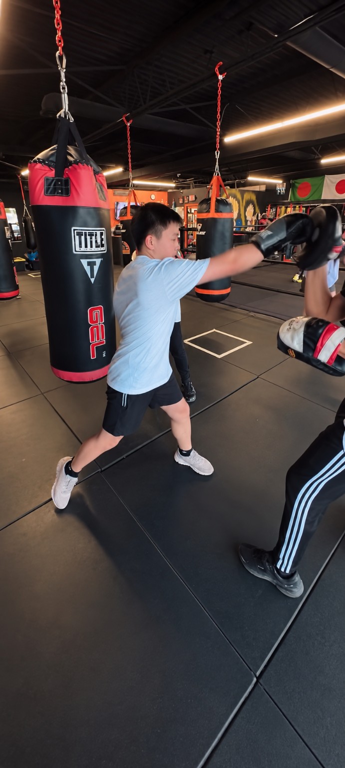A young boxer practices a straight punch during mitt training