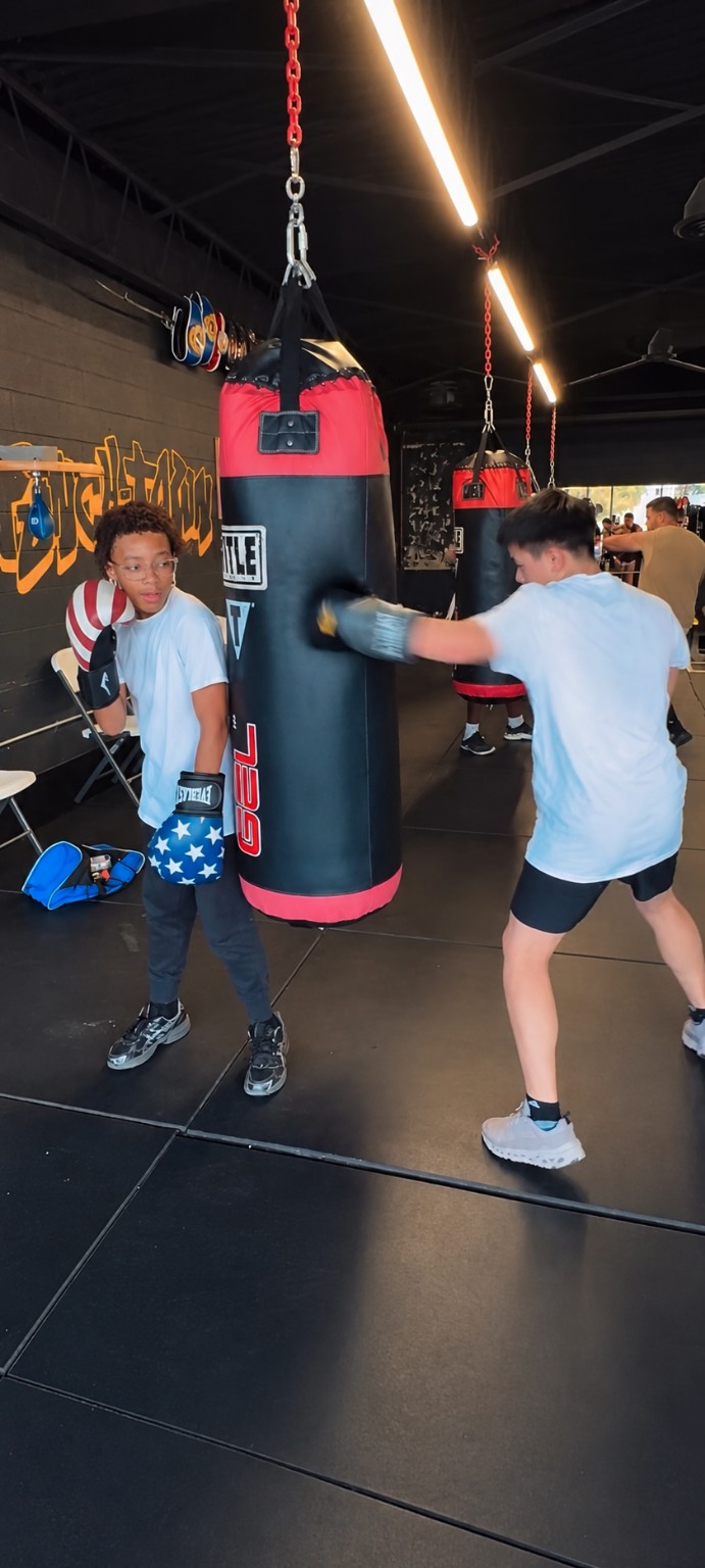 Young boxers train beside a heavy bag on the PunchTown gym floor