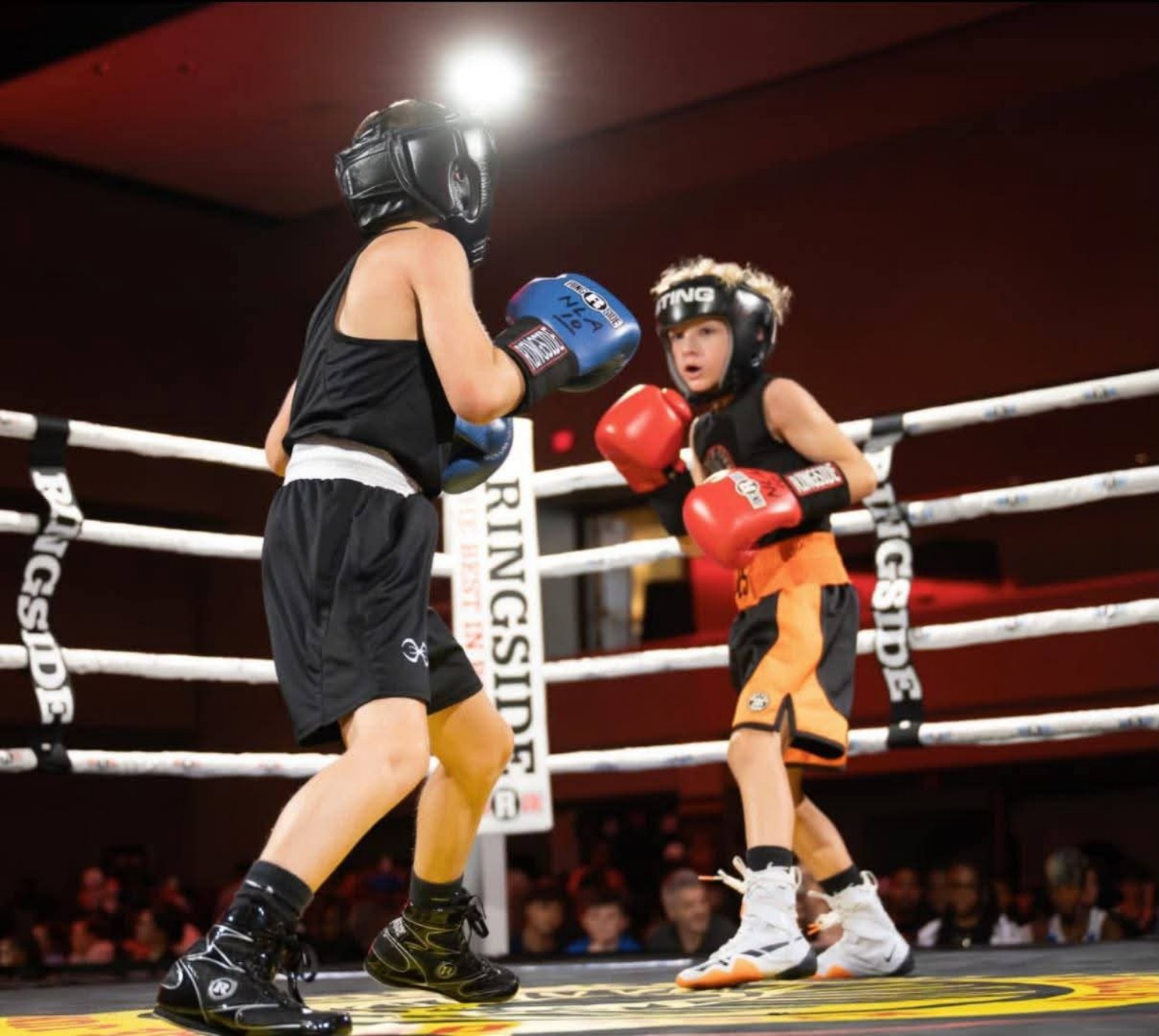 Two youth boxers in headgear compete in the ring during an amateur bout