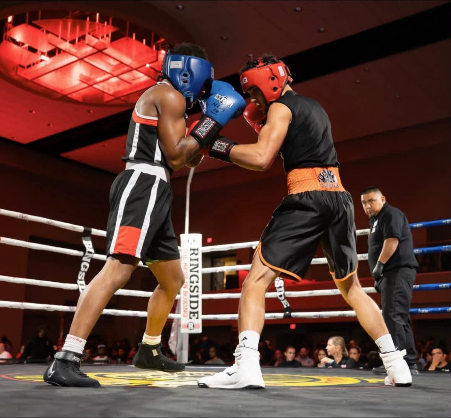 Two amateur boxers exchange close-range punches in the ring