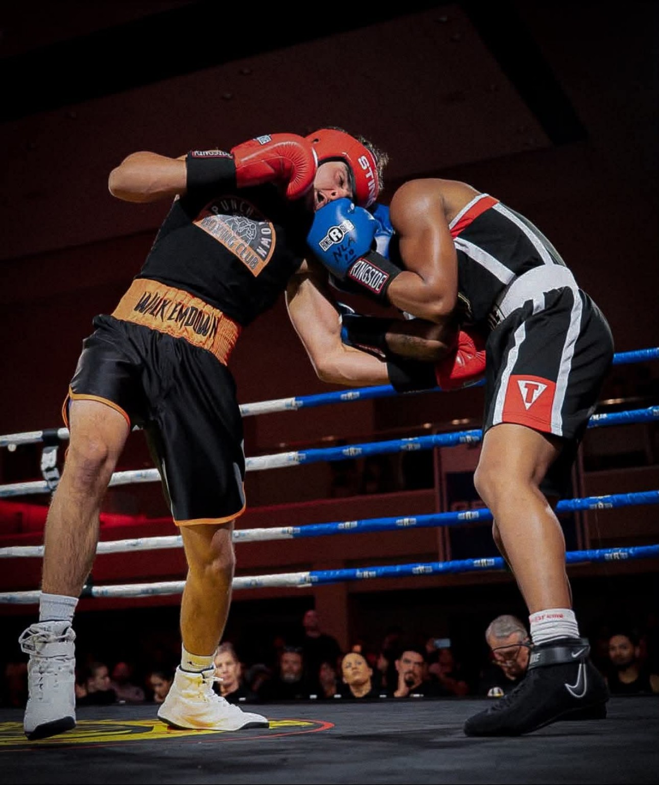 Two amateur boxers clinch during a competitive bout