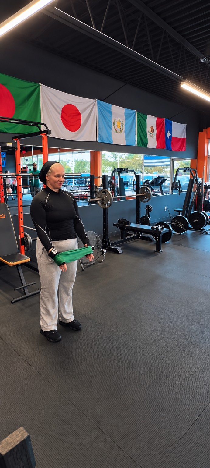 Woman wrapping her hands with green hand wraps on the gym floor beneath hanging flags